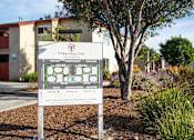 Thumbnail 9 of 33 - A sign for Whispering Oaks Apartments stands in front of a building.