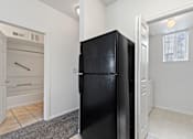 Thumbnail 9 of 19 - A black fridge in a room with white walls.