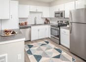 Thumbnail 4 of 29 - A kitchen with white cabinets and a rug on the floor.