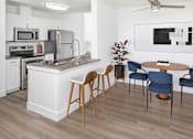 Thumbnail 5 of 29 - A modern kitchen with a white island, wooden chairs, and a ceiling fan.