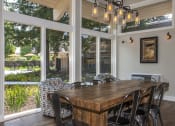 Thumbnail 18 of 25 - Lounge with wood floors, view of grounds, communal wood table, metal chairs, hip lighting, armchairs