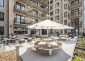 Thumbnail 28 of 29 - an outdoor patio with tables and an umbrella in an apartment building