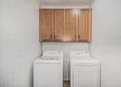 Thumbnail 16 of 23 - Two white front load washing machines in a laundry room at Bloom Rental Living apartments in Fort Collins, CO.
