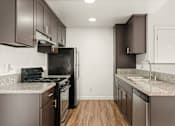 Thumbnail 11 of 33 - A kitchen with brown cabinets and a black fridge.