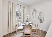 Thumbnail 9 of 37 - A dining room with a table set for two and a vase of white flowers.