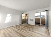Thumbnail 24 of 36 - A room with wooden floors and a white wall with a door leading to a balcony.