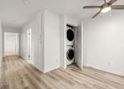 Thumbnail 31 of 36 - A room with a white ceiling and a fan, and a washing machine in the corner.
