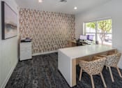 Thumbnail 19 of 29 - A room with a desk and chairs with a patterned wallpaper.