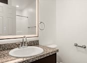 Thumbnail 25 of 33 - A bathroom with a sink, mirror, and toilet.