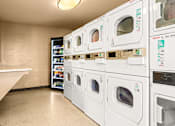 Thumbnail 32 of 36 - A row of washing machines are lined up in a laundromat.