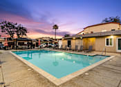 Thumbnail 2 of 33 - A pool surrounded by chairs and a building in the background.