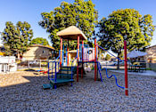 Thumbnail 6 of 36 - A playground with a red and blue swing set and a yellow canopy.