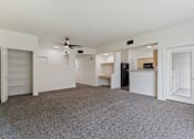 Thumbnail 18 of 36 - A spacious room with a ceiling fan and a kitchenette in the background.