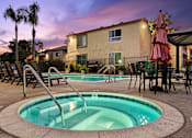Thumbnail 4 of 33 - A hot tub sits in the middle of a pool surrounded by chairs and umbrellas.