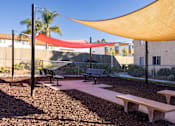 Thumbnail 7 of 36 - A playground with a red and yellow shade structure.