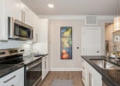 Thumbnail 2 of 24 - a kitchen with black counter tops and white cabinets