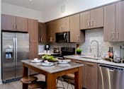 Thumbnail 46 of 46 - A modern kitchen with a stainless steel refrigerator and a wooden dining table set with plates.