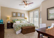 Thumbnail 15 of 29 - A bedroom with a bed, a chair, and a ceiling fan.