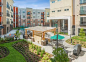 Thumbnail 16 of 24 - an outdoor patio area with tables and umbrellas in an apartment building