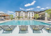Thumbnail 1 of 24 - a swimming pool with lounge chairs and buildings in the background