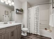 Thumbnail 10 of 48 - Bathroom with white countertop and striped shower curtain at Canyon Creek Apartments, Wilsonville, OR 97070