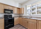 Thumbnail 10 of 36 - A kitchen with wooden cabinets and black appliances.