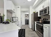 Thumbnail 6 of 48 - A modern kitchen with white cabinets and stainless steel appliances.