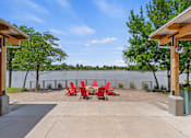 Thumbnail 43 of 52 - A patio with red chairs and a view of a lake.