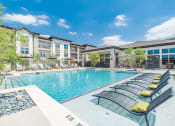Thumbnail 5 of 24 - a swimming pool with lounge chairs in front of an apartment building