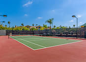 Thumbnail 23 of 29 - A tennis court with a red surface and green boundary lines.
