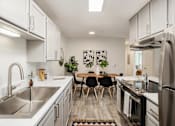Thumbnail 12 of 48 - White galley kitchen with dining table and modern chairs at Canyon Creek Apartments, Wilsonville, 97070