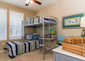 Thumbnail 14 of 29 - A room with a bed, a desk, and a fan.