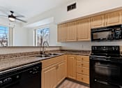 Thumbnail 11 of 36 - A kitchen with black appliances and wooden cabinets.