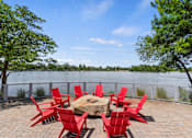 Thumbnail 19 of 52 - A table surrounded by red chairs is on a patio overlooking a body of water.