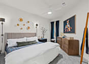 Thumbnail 12 of 20 - A bedroom with a bed, nightstand, and a painting on the wall.