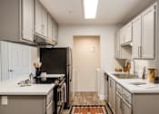 Thumbnail 13 of 48 - Galley kitchen with white counters and pendant lighting at Canyon Creek Apartments, Wilsonville, Oregon