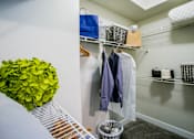 Thumbnail 14 of 44 - A closet with clothes hanging and baskets on the shelves.