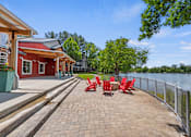 Thumbnail 20 of 52 - A red building with a white roof is situated next to a body of water with a red bench in front of it.