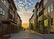 Thumbnail 24 of 28 - A sunset view of a street lined with modern apartment buildings.