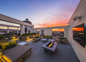 Thumbnail 4 of 34 - A rooftop patio with a fire pit and seating area.