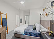 Thumbnail 2 of 20 - A bedroom with a bed, a mirror, and a ceiling fan.
