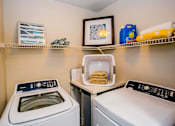 Thumbnail 15 of 44 - A laundry room with a washer and dryer and a basket of towels.