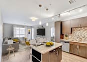 Thumbnail 1 of 28 - A modern kitchen with a dining area and a living room.
