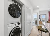 Thumbnail 34 of 55 - A modern laundry room with a washing machine and dryer built into the wall.