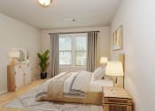 Thumbnail 24 of 60 - a bedroom with a bed and a nightstand with a lamp on it
