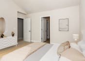 Thumbnail 25 of 60 - a bedroom with a white bedspread and a white dresser with a mirror