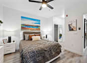 Thumbnail 11 of 48 - A bedroom with a bed, a ceiling fan, and a painting on the wall.