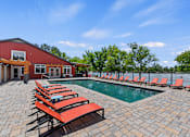 Thumbnail 31 of 52 - A pool area with red sun loungers and a red building.