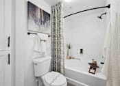 Thumbnail 14 of 48 - A white toilet sits next to a white bathtub in a bathroom.