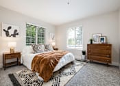 Thumbnail 18 of 48 - Spacious bedroom with white bedding and patterned throw at Canyon Creek Apartments, Wilsonville, OR